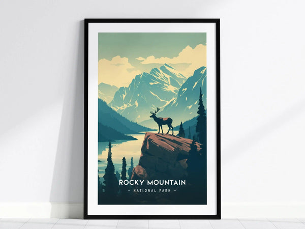 A framed minimalist poster depicting a lone elk standing on a cliff, overlooking mountain ranges and a reflective lake under a serene sunrise. Text reads Rocky Mountain National Park.