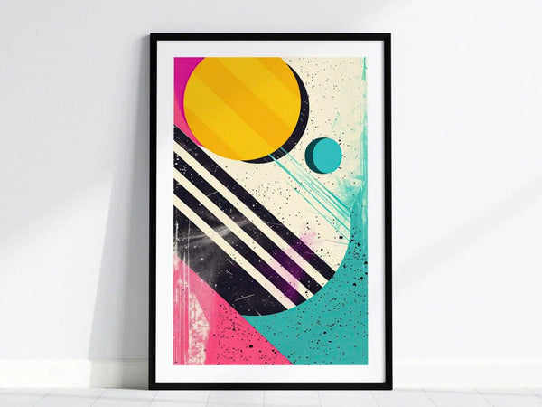 A framed poster featuring bold geometric shapes, including a large yellow circle, black diagonal stripes, and vibrant splashes of pink and teal, creating a retro 1980s aesthetic.