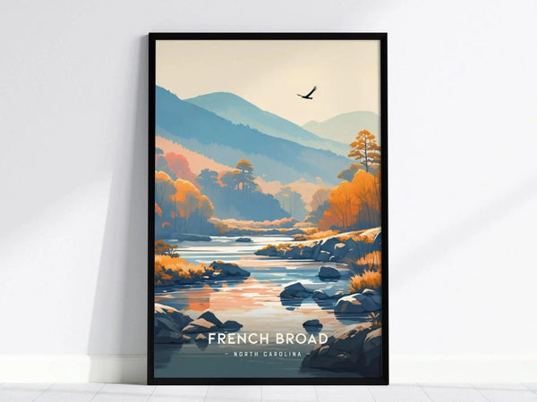 Framed artwork depicting the French Broad River in North Carolina, featuring a serene landscape with mountains, autumn trees, and a bird soaring in the sky.