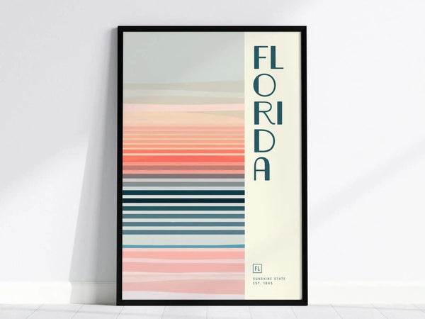 A framed poster with vertical text reading FLORIDA alongside horizontal pastel stripes in pink, blue, and beige tones, evoking a minimalist design. The bottom reads Sunshine State Est. 1845.