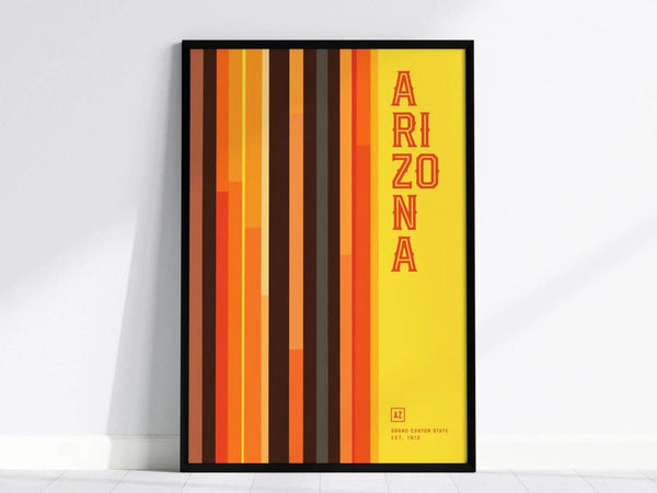 A framed poster with vertical stripes in shades of orange, brown, and yellow, featuring the word ARIZONA in bold red letters on the right.