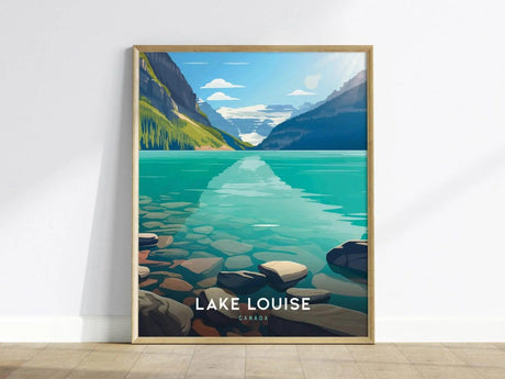A framed poster of Lake Louise featuring turquoise waters, rocky shores, and mountainous landscapes under a clear blue sky, leaning against a white wall on a wooden floor.