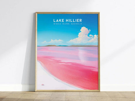 Framed poster of Lake Hillier, showcasing vibrant pink water against a blue sky with fluffy clouds, displayed on a light wooden floor.