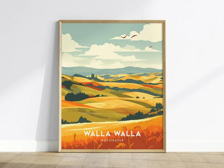 Framed poster of Walla Walla, Washington, depicting colorful rolling hills and fields under a partly cloudy sky with birds. The artwork is propped against a white wall.