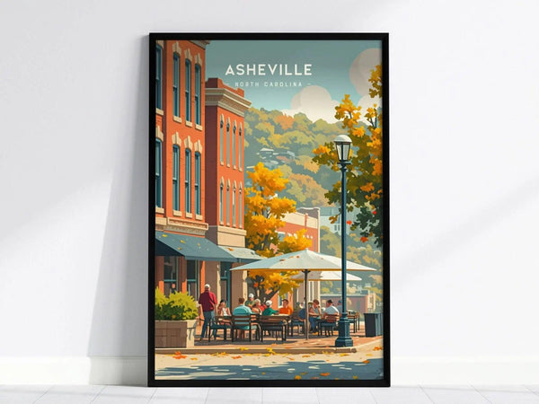 A framed poster depicting Asheville, North Carolina, features vibrant autumn colors, outdoor cafés, and historic buildings against a backdrop of the Blue Ridge Mountains.
