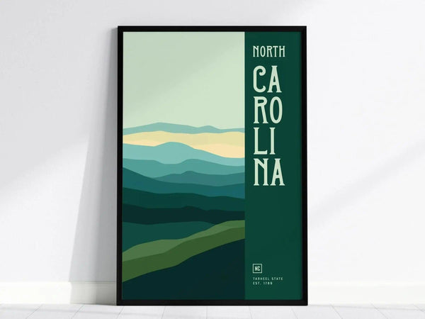 Framed minimalist poster featuring stylized rolling green hills and the text North Carolina in bold letters. The design captures a serene landscape with layered mountain silhouettes.