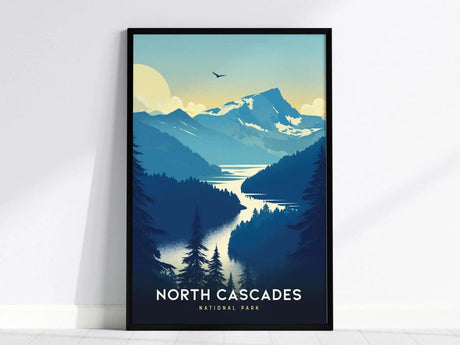 Framed poster of North Cascades National Park featuring a stylized landscape with mountains, a lake, and trees under a yellow sky. A bird is flying above the scene.