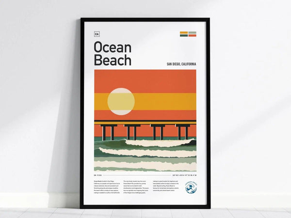 Framed poster featuring a stylized illustration of Ocean Beach in San Diego, showing a pier at sunset with vibrant orange and yellow hues, placed against a plain white wall.