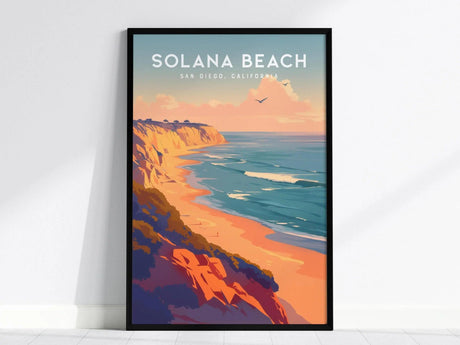 A framed poster of Solana Beach, San Diego, California, showcasing vibrant coastal cliffs, ocean waves, and birds in a pastel sunset sky.