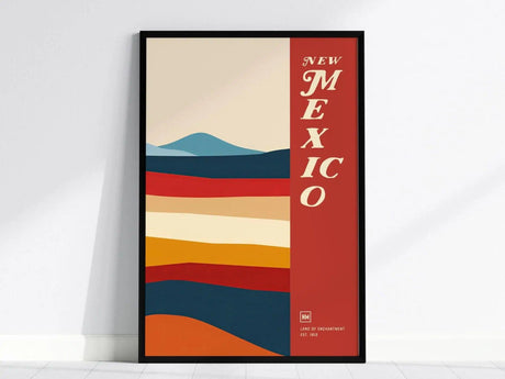 Framed poster featuring abstract, colorful horizontal stripes resembling a desert landscape, with New Mexico in bold text on a red vertical band.