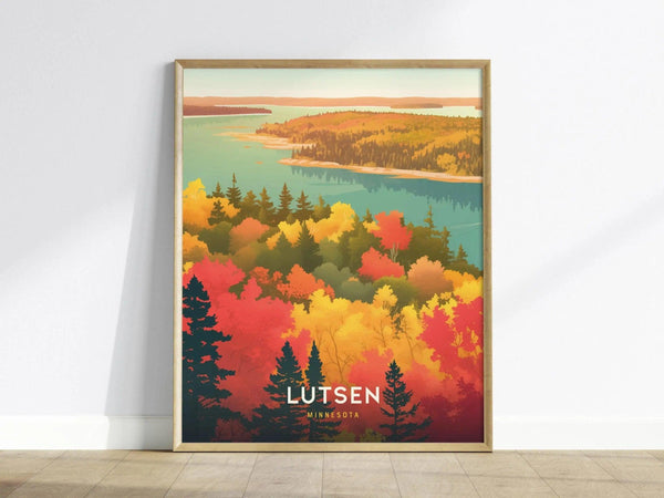 A framed poster depicting vibrant autumn foliage with red, orange, and yellow trees overlooking a blue lake. The word Lutsen is printed at the bottom.