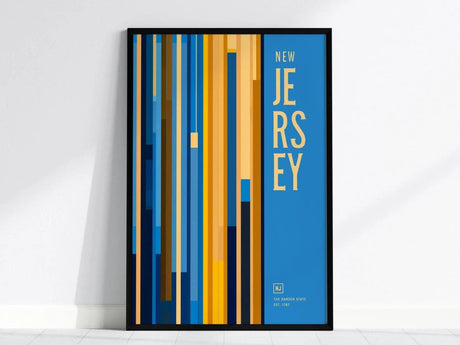Framed poster featuring vertical stripes in blue, yellow, and brown hues with New Jersey text on a blue background. The poster leans against a white wall for display.