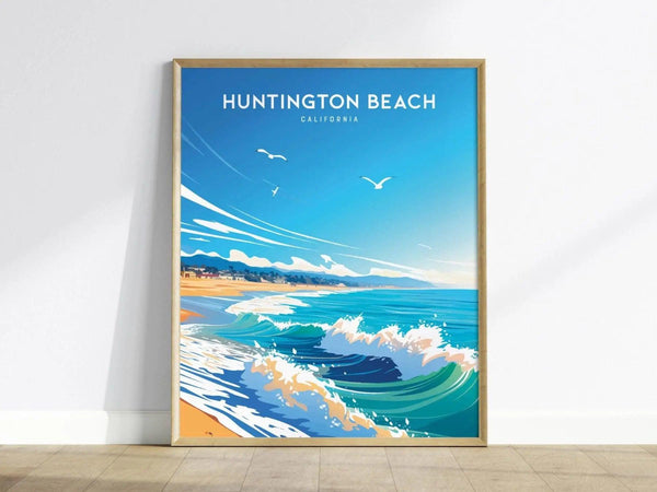 A framed Huntington Beach poster features a stylized ocean scene with waves, sandy shoreline, and seagulls under a bright blue sky, leaning against a white wall.