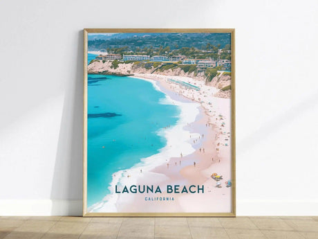 Framed poster depicting a scenic aerial view of Laguna Beach, California, featuring turquoise waters, sandy shoreline, and coastal buildings under a clear sky. Text reads Laguna Beach, California.