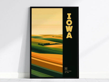 Framed Iowa poster featuring stylized rolling prairies with green and golden hues, and bold yellow text reading IOWA on a dark background. Perfect for modern home decor.
