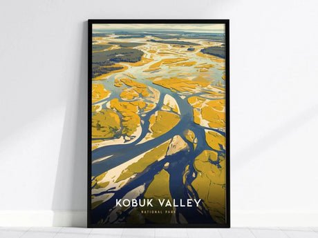 A framed poster depicting abstract aerial views of Kobuk Valley with flowing rivers and sand dunes in warm earth tones, set against a white wall.