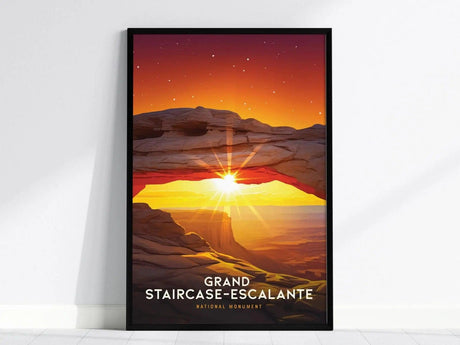 A framed poster of Grand Staircase–Escalante features a vibrant sunset with a sunburst through a rocky arch, set against a starry sky. The words Grand Staircase-Escalante are visible.
