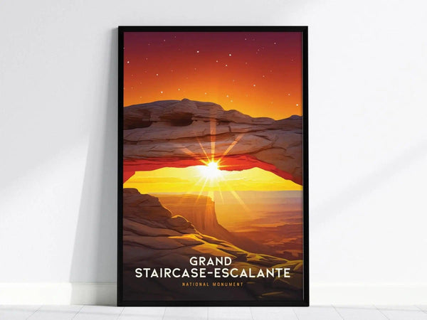 A framed poster of Grand Staircase–Escalante features a vibrant sunset with a sunburst through a rocky arch, set against a starry sky. The words Grand Staircase-Escalante are visible.