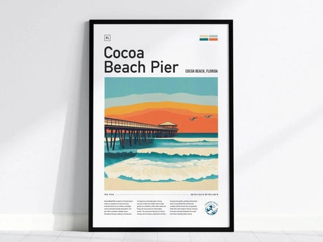 Framed poster featuring a stylized illustration of Cocoa Beach Pier with vibrant waves and an orange sunset sky. The artwork includes seagulls and a wooden pier extending over the ocean.