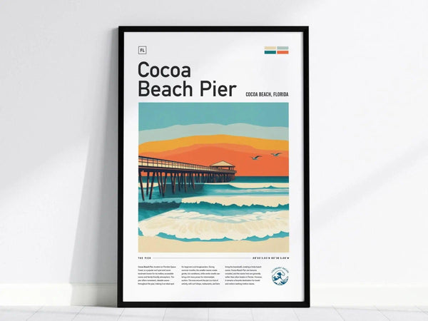 Framed poster featuring a stylized illustration of Cocoa Beach Pier with vibrant waves and an orange sunset sky. The artwork includes seagulls and a wooden pier extending over the ocean.