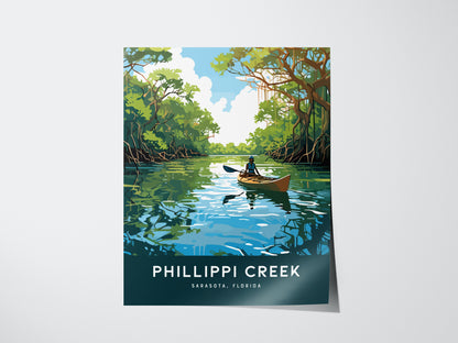 A poster depicts a serene scene of a kayaker paddling through a mangrove-lined creek under a blue sky. The words Phillippi Creek, Sarasota, Florida are displayed at the bottom.