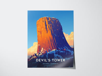 A vibrant poster depicts Devils Tower against a clear blue sky, with warm orange hues highlighting the geological formation. Text reads Devils Tower National Monument at the bottom.