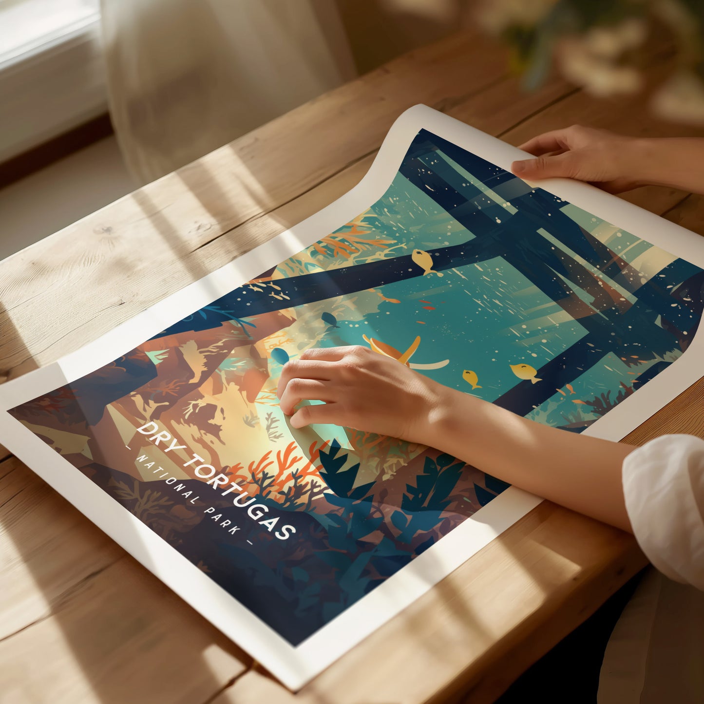 A person holds a colorful, illustrated poster of Dry Tortugas National Park featuring marine life and coral reefs, placed on a wooden table with sunlight streaming.
