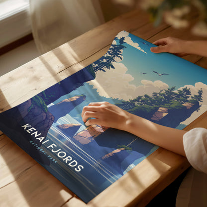 A person is holding a vibrant Kenai Fjords National Park poster featuring illustrated cliffs, trees, and birds under a blue sky.