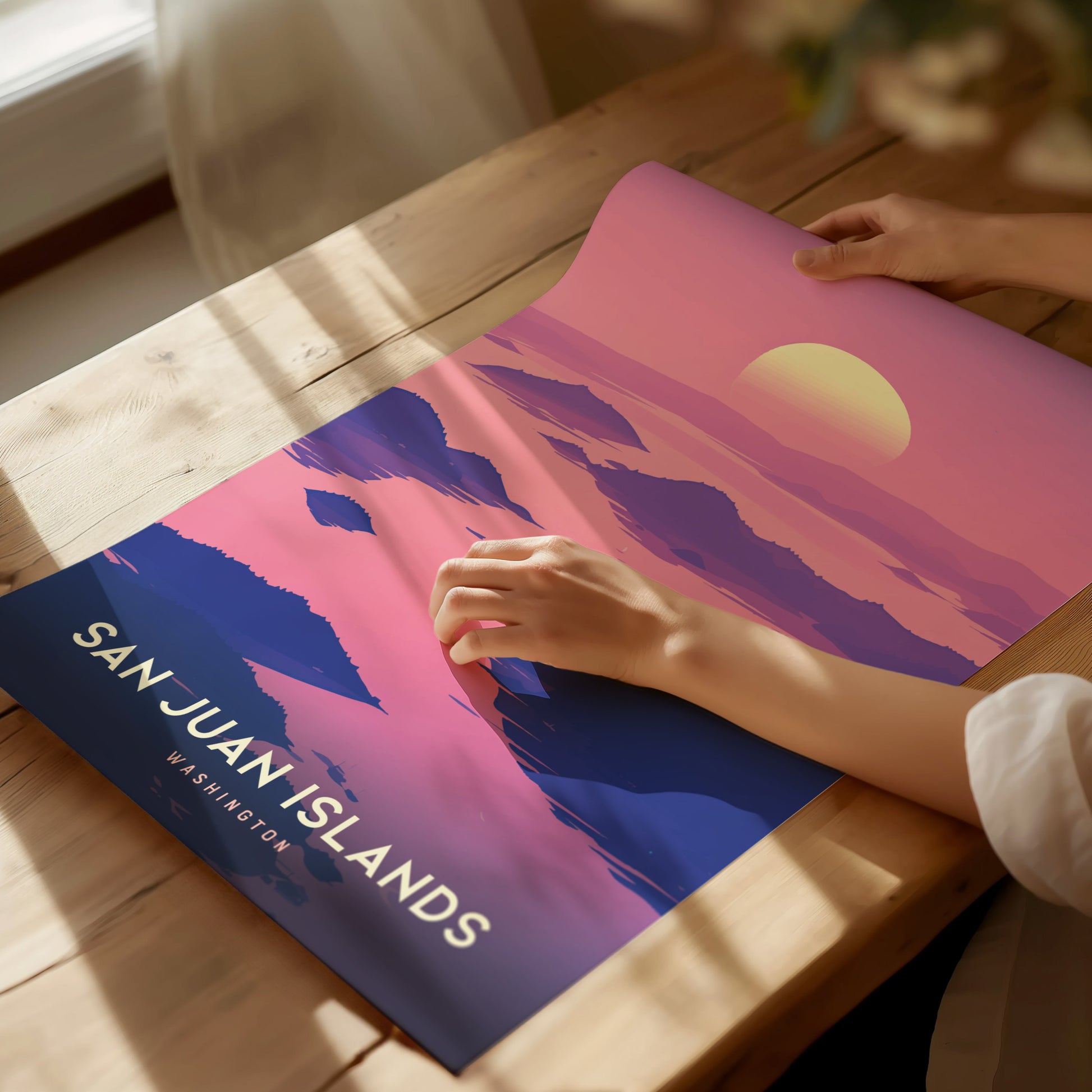 A person is holding a colorful poster titled San Juan Islands Washington, featuring a scenic sunset with pink and purple hues over abstract landscapes.
