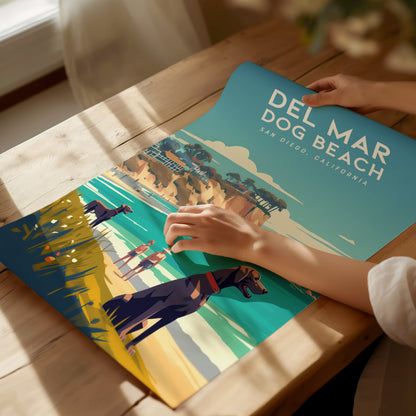 A person unrolls a colorful poster featuring Del Mar Dog Beach in San Diego, California, depicting dogs playing near the ocean with cliffs in the background.