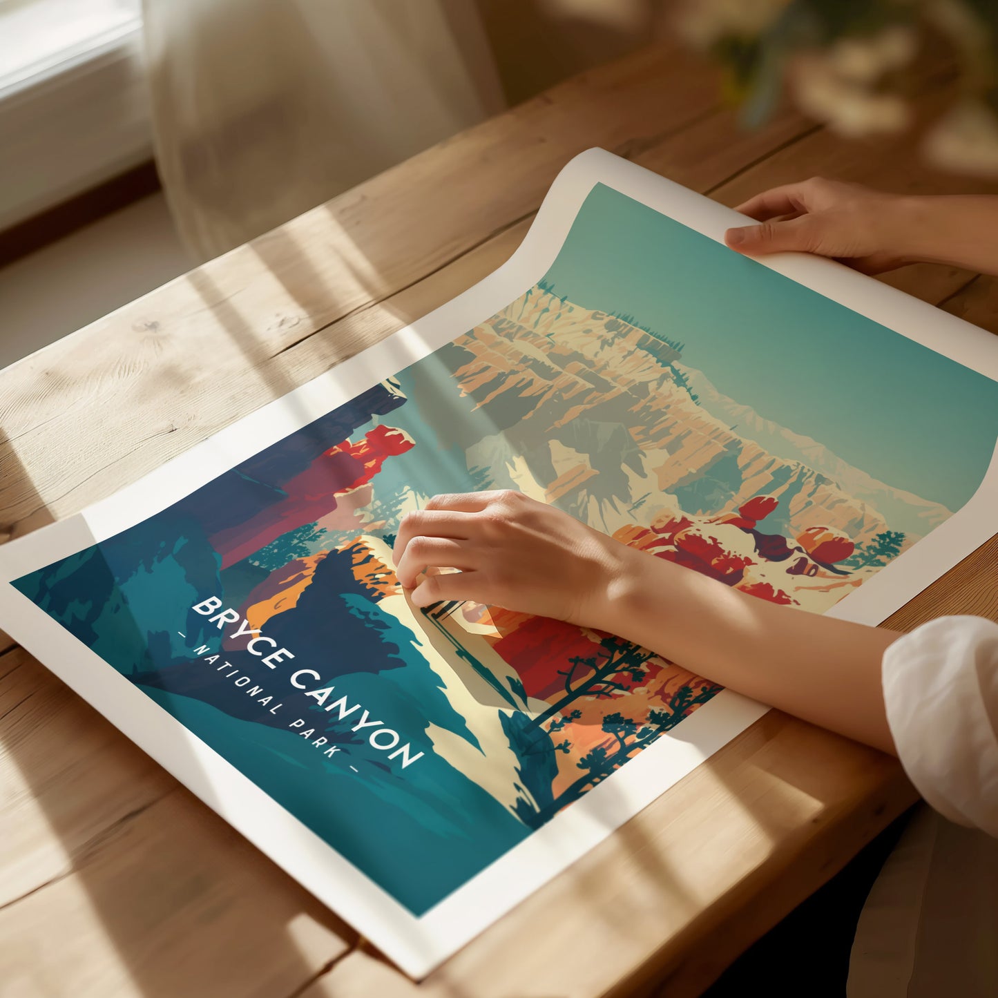 A person holds a vibrant Bryce Canyon National Park print, showcasing colorful rock formations and a clear blue sky, on a wooden table with soft lighting.