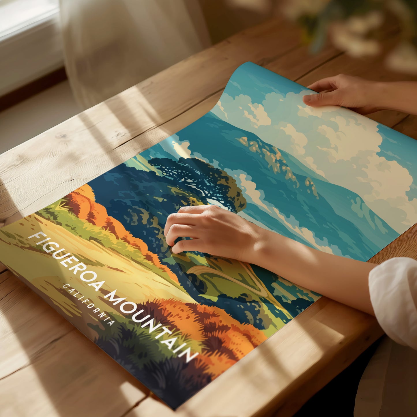 A person is holding a vibrant poster featuring a scenic view of Figueroa Mountain, California, with rolling hills and colorful wildflowers. The poster includes the text FIGUEROA MOUNTAIN prominently displayed at the bottom.