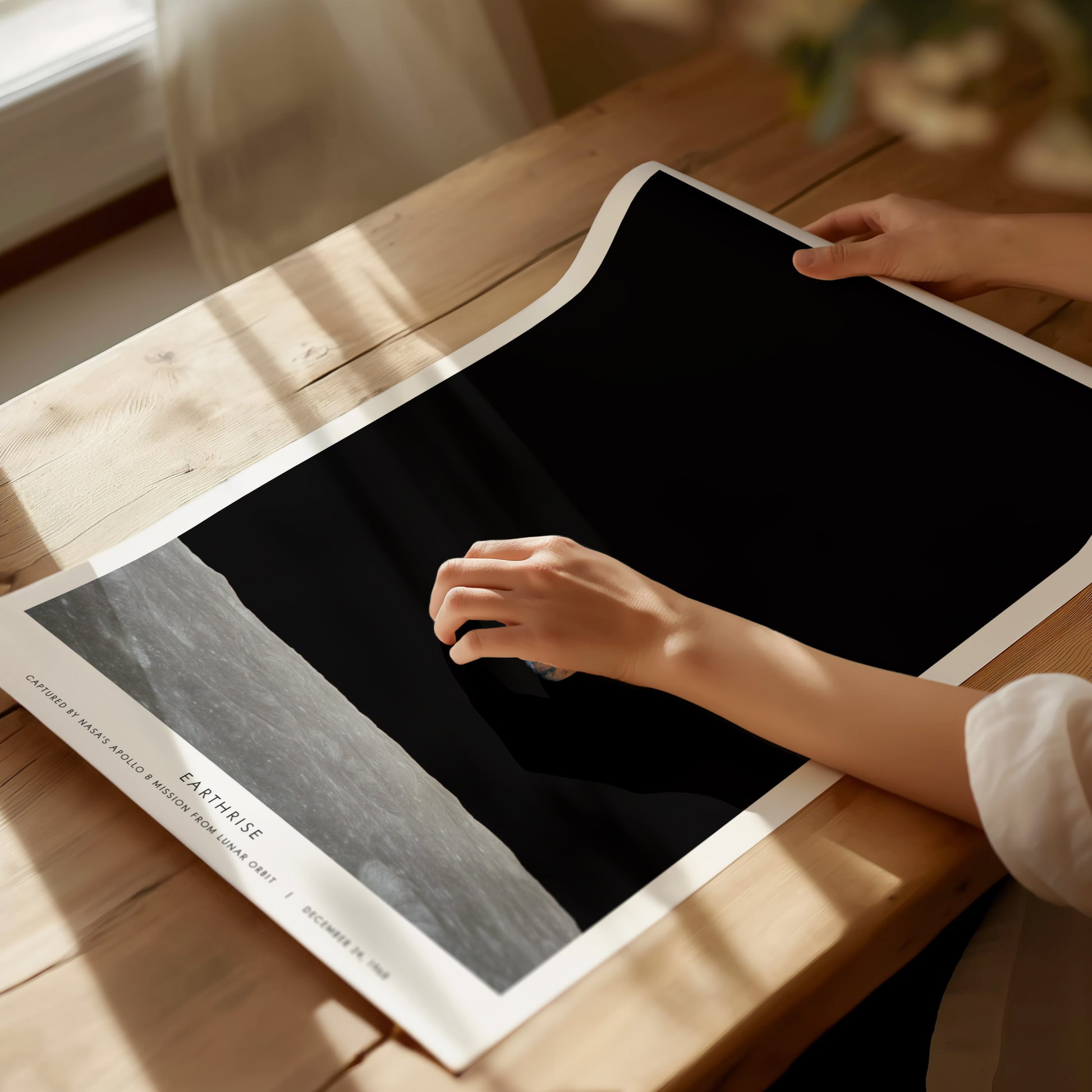 Unframed Earthrise NASA poster printed on matte archival paper laid flat on a tabletop