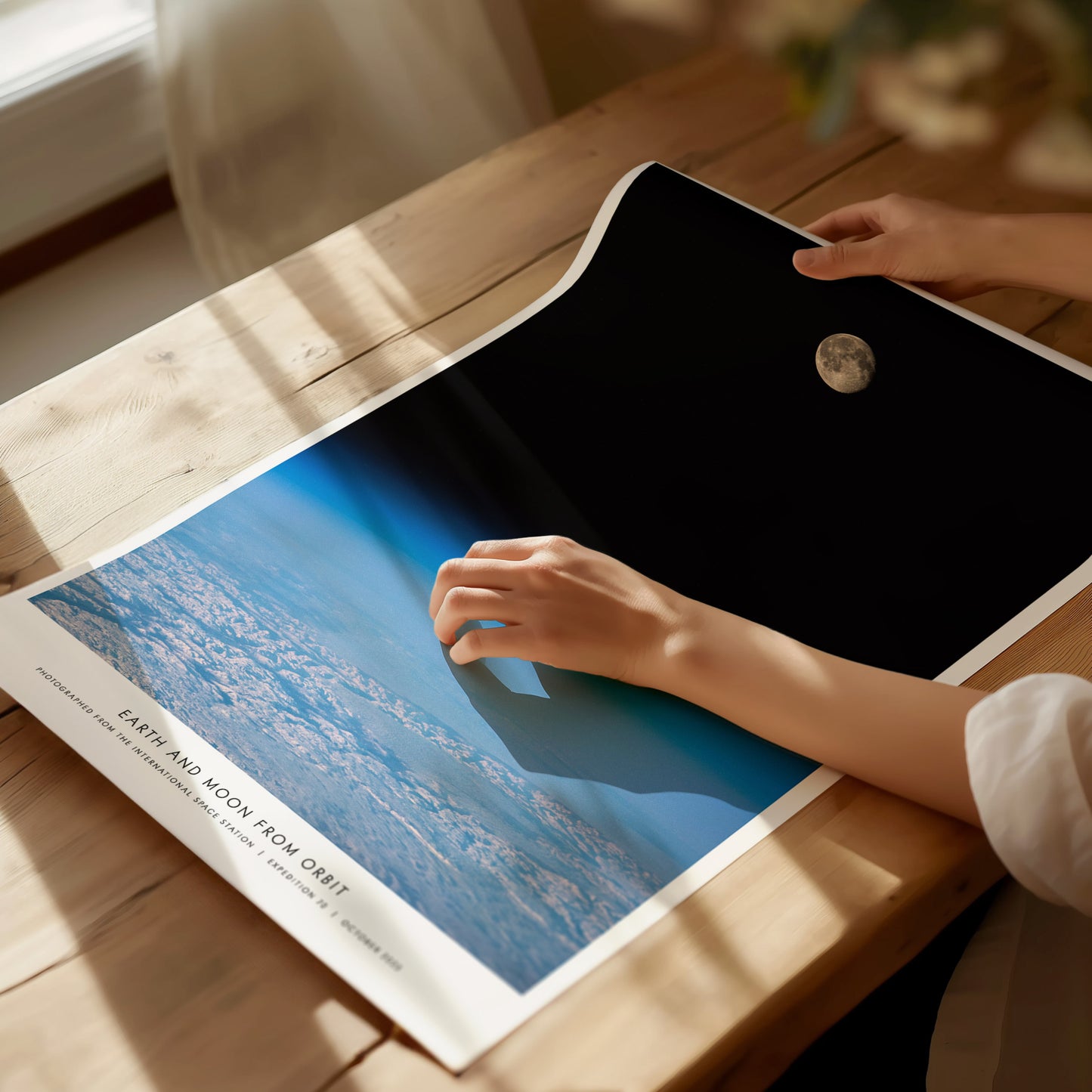 Unframed Earth and Moon Orbit NASA poster printed on matte archival paper laid flat on a tabletop