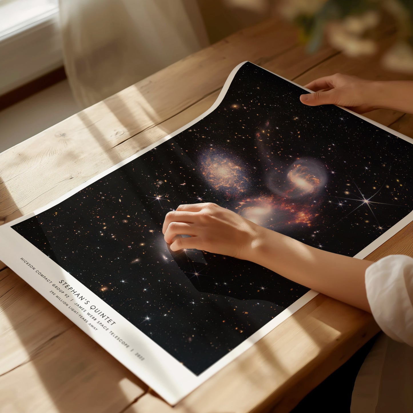 Person holding a star poster with a nebula design on a wooden table