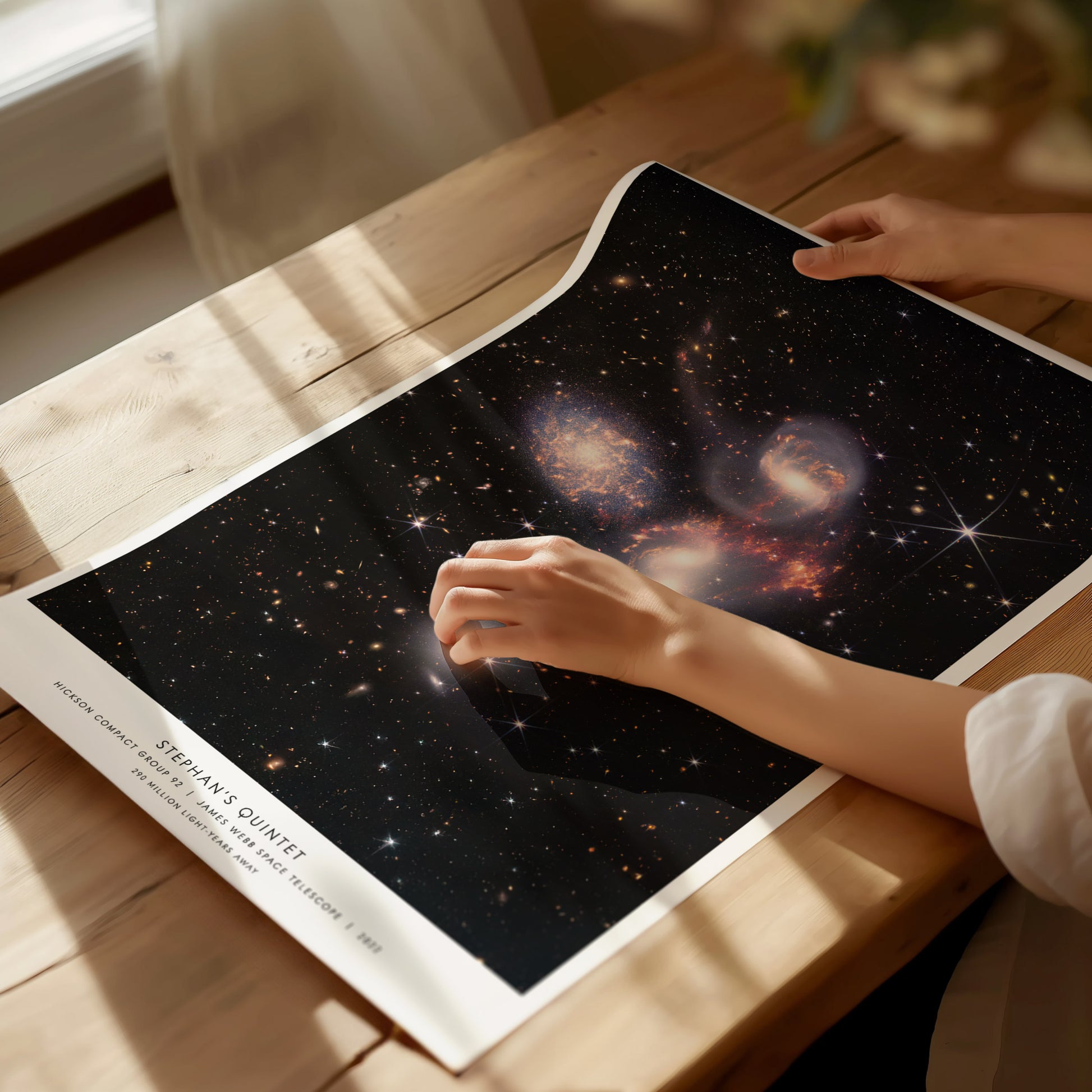 Person holding a star poster with a nebula design on a wooden table