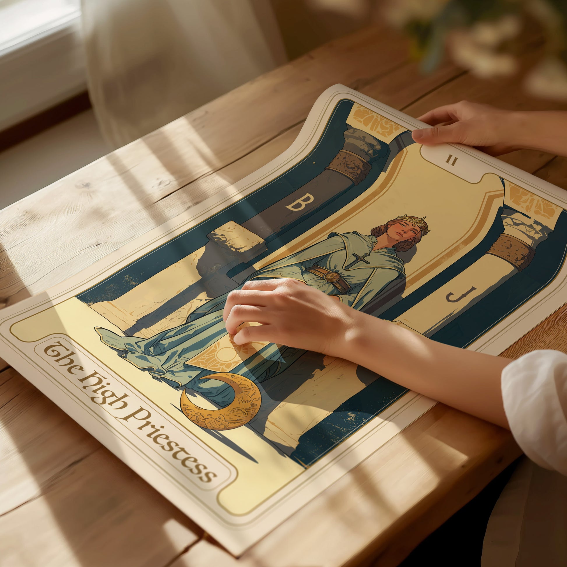 A person holds a High Priestess Tarot Poster on a wooden table, featuring a serene figure between two pillars marked B and J with soft, natural lighting.