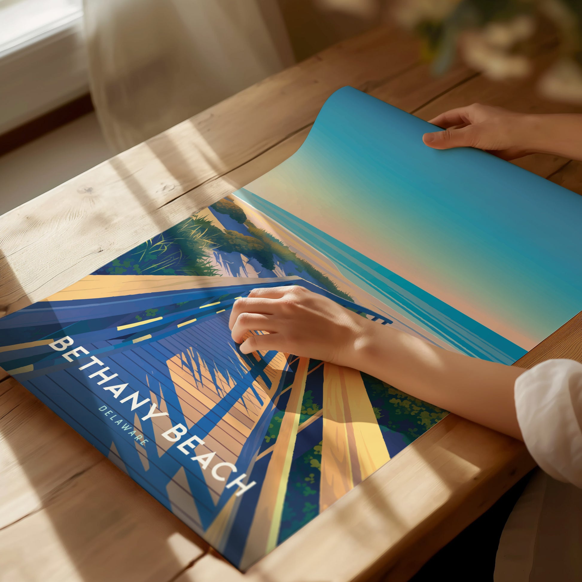 A person is examining a vibrant Bethany Beach poster depicting a wooden boardwalk leading to the ocean, with warm tones and coastal scenery, on a wooden table.