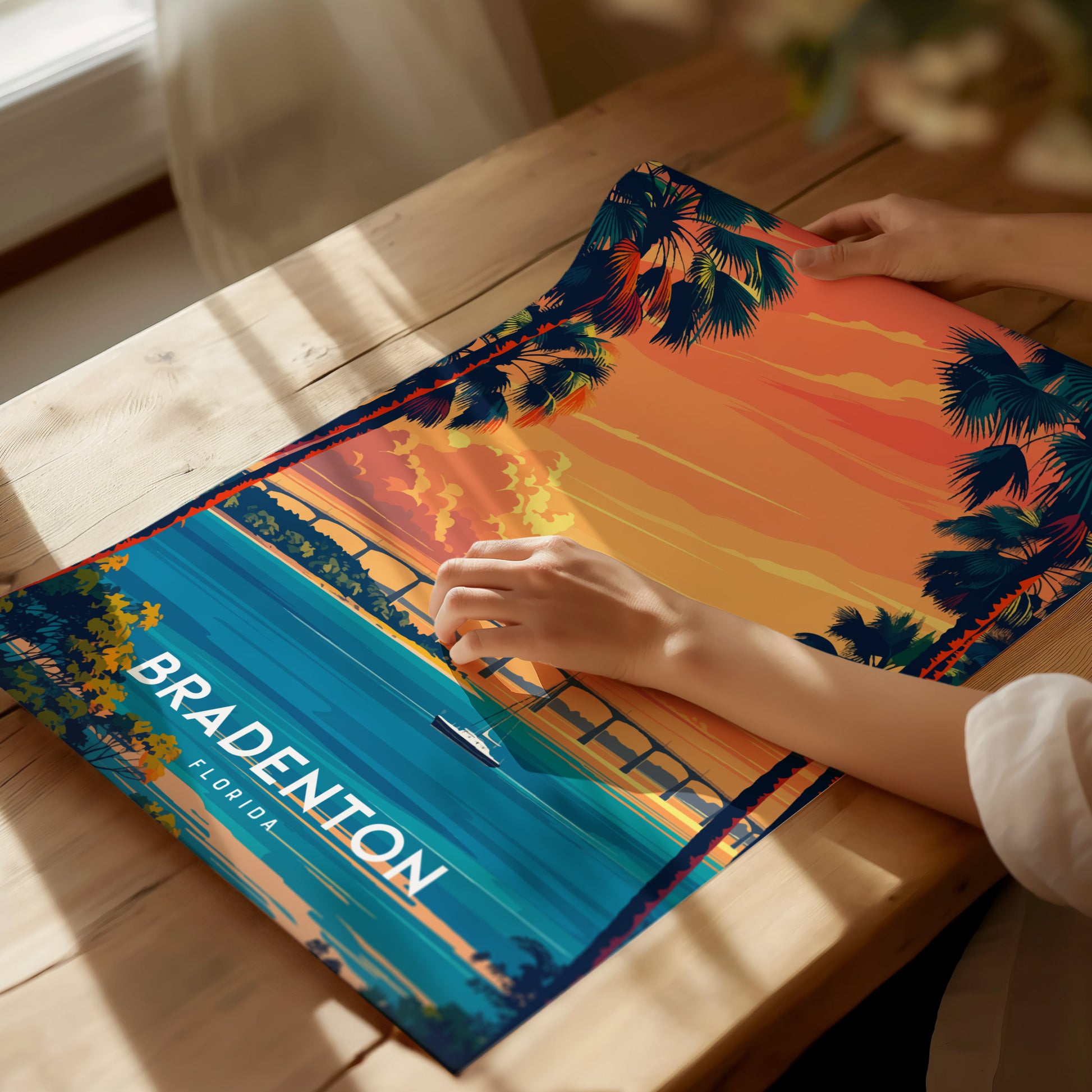 Person holding a colorful poster of Bradenton, Florida on a wooden table.
