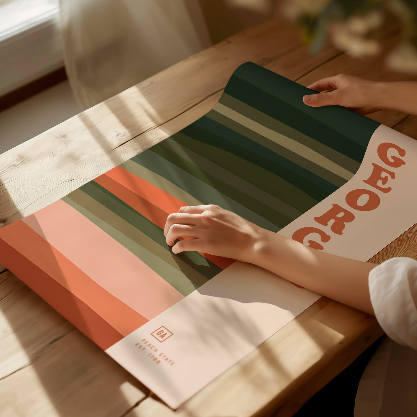 A person is holding a colorful poster with bold, wavy stripes in green, peach, and orange tones, featuring the word Georgia in large letters.