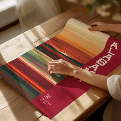 A person holds a colorful abstract poster with vertical stripes in warm tones, placed on a wooden table. The poster features bold white text and artistic elements.