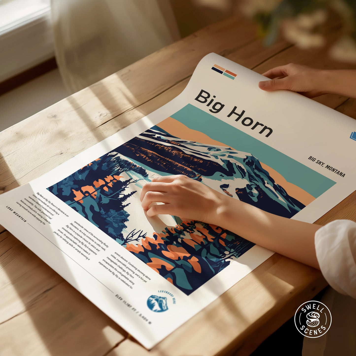 A person adjusts a colorful poster titled Big Horn featuring a stylized landscape of mountains and trees.
