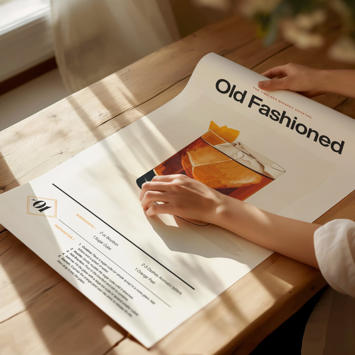 A person is holding an Old Fashioned cocktail poster with a detailed whiskey recipe on a wooden table, bathed in warm sunlight.