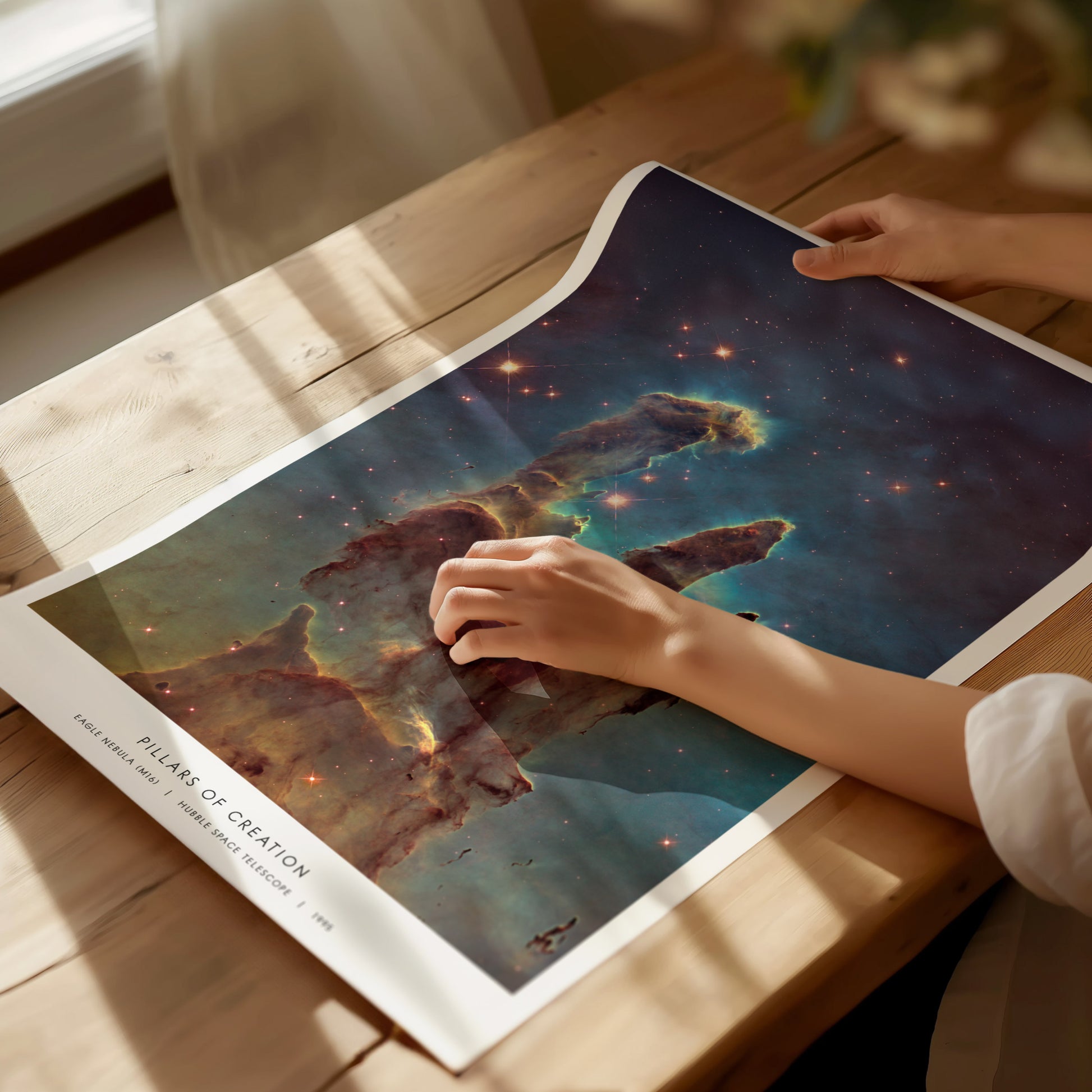 Unframed Pillars of Creation NASA art print laid flat on a tabletop with astronomy books