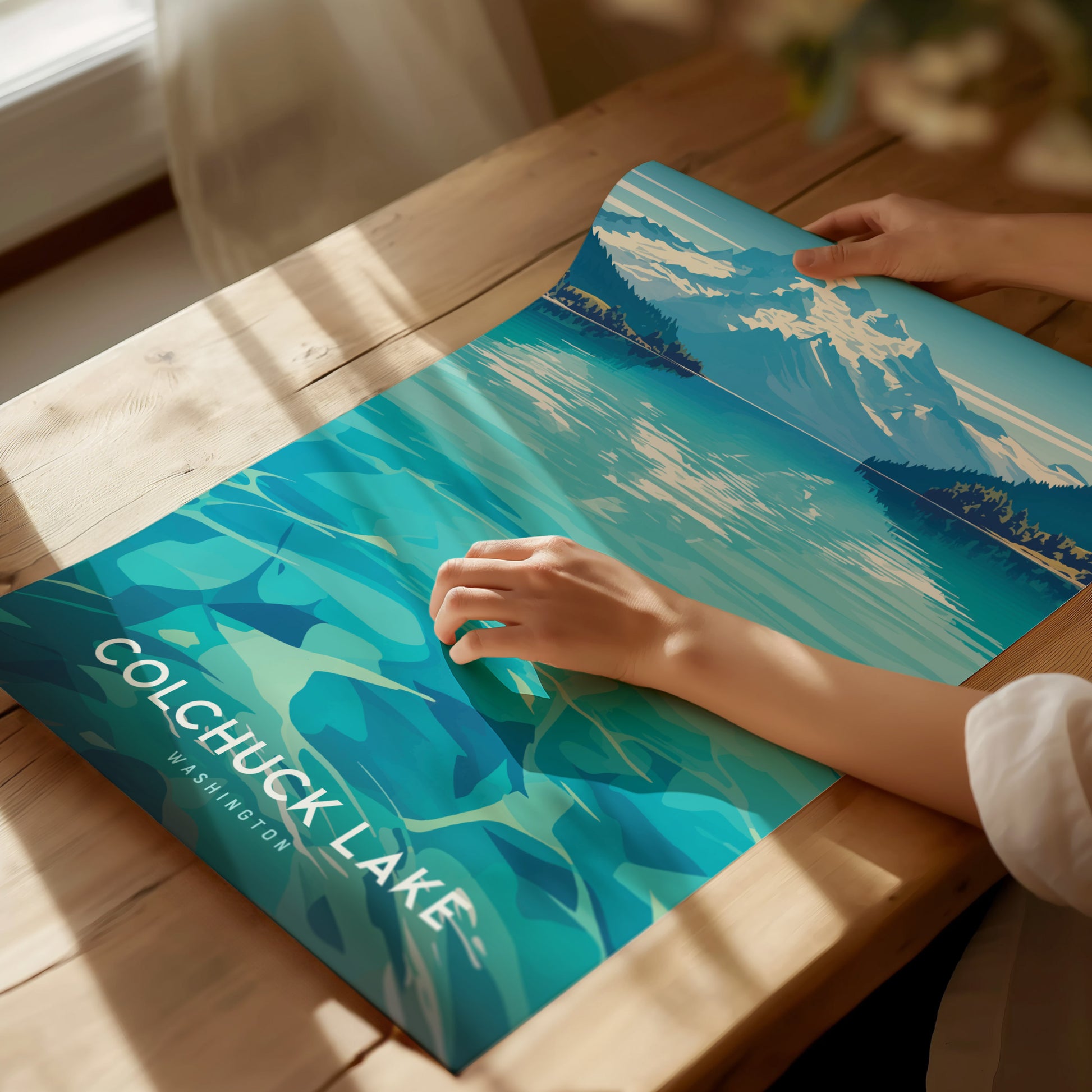 A person unrolls a vibrant poster of Colchuck Lake, Washington, featuring turquoise waters and mountainous scenery.