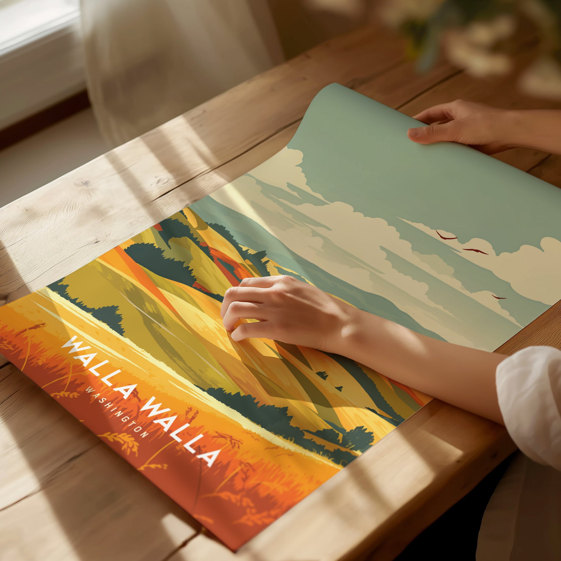 A person unrolls a colorful poster on a wooden table, depicting Walla Walla, Washington with vibrant landscapes and skies. Sunlight streams through a nearby window, casting shadows.