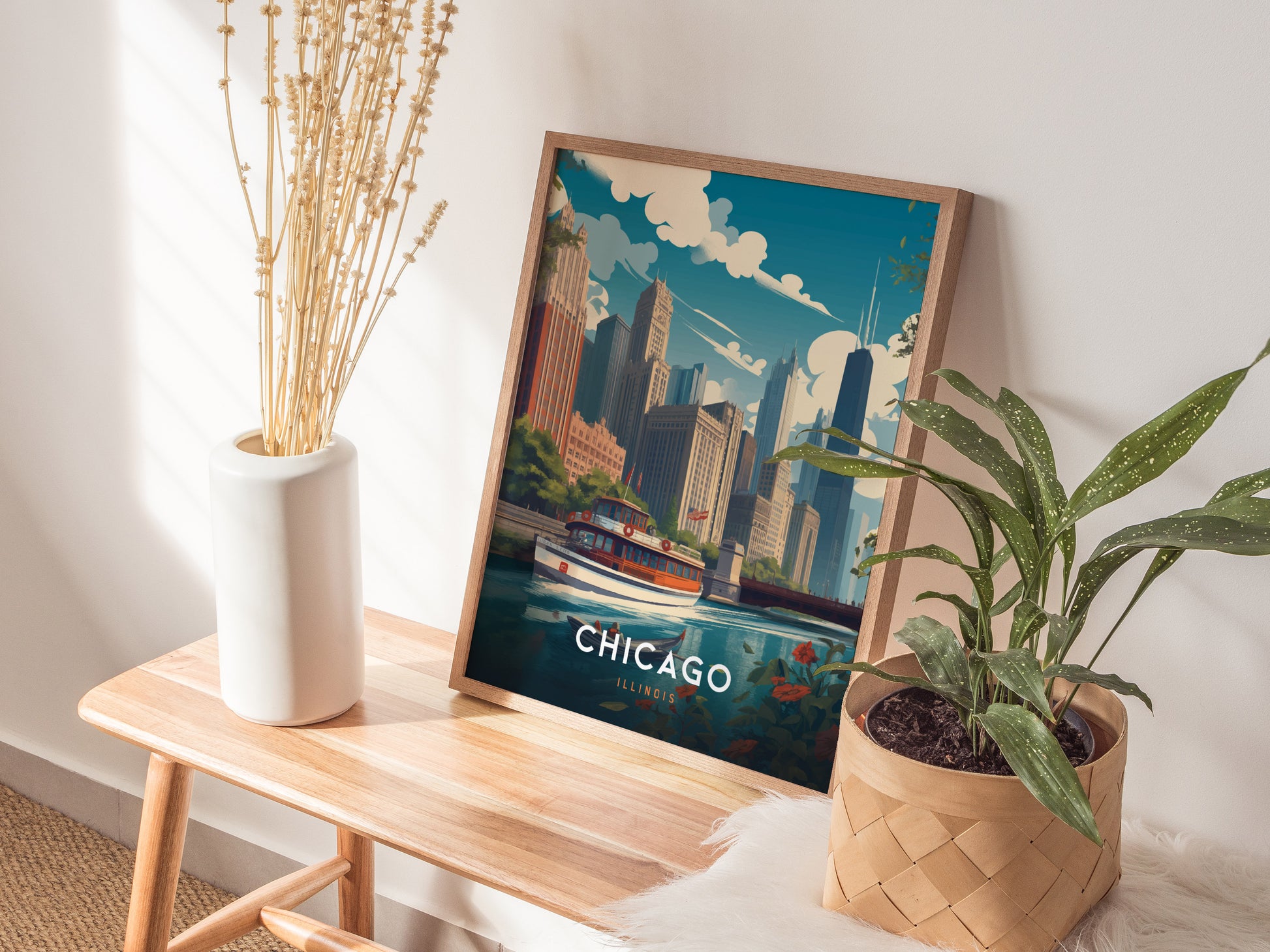A framed poster of Chicagos skyline and river is placed on a wooden bench, accompanied by a white vase with dried stems and a potted green plant.