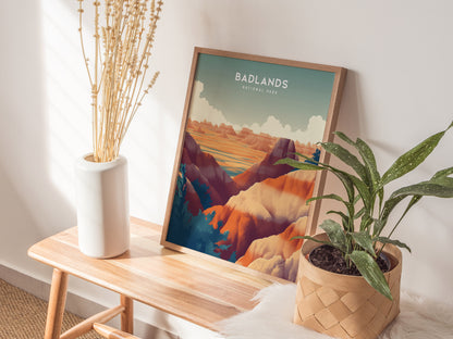 A framed Badlands National Park poster rests on a wooden bench, accompanied by a white vase with dried flowers and a potted green plant, creating a cozy, natural setting.