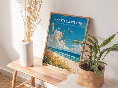 A framed Anastasia Island poster rests on a wooden bench, surrounded by a white vase with dried flowers and a potted green plant. Sunlight filters through, casting soft shadows.