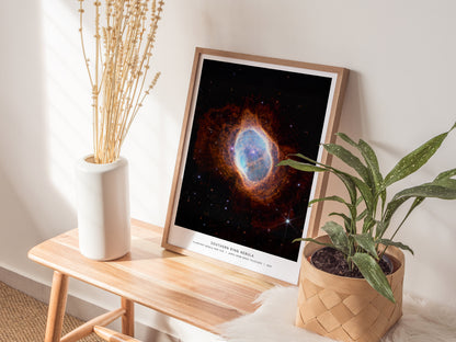Natural wood framed Southern Ring Nebula space print leaning on a shelf beside plants and neutral accessories